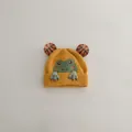 Detail der gelben Baby-Strickmütze mit süßem grünen Frosch-Cartoon und Augen-Pompons - 1-3 Jahre (47-52cm) / Gelb