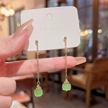 Detail view of long gold tassel earrings with green square stone drops and thin metal chains - A1092 Gold