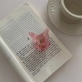 Rosa Schmetterlings-Haarklammer aus Acetat auf einem antiken Buch liegend - Fluoreszierendes Rosa