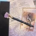 Detail of creative metal ballpoint pen featuring raw purple crystal top on vintage paper - Amethyst