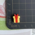 Macro shot of a tiny yellow resin gift box charm with a red bow showing 1cm scale - 07-Red and Yellow Gift Box