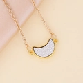 Primer plano del collar de luna dorada con purpurina plateada sobre seda rosa - Blanco