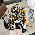 Long silk-feel scarf with bold abstract gold and black prints on a beige knit sweater - Black