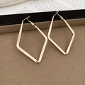 Macro shot of large golden geometric rhombus earrings on a dark velvet display tray - Gold - Large