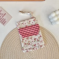 Close-up of floral canvas nurse pouch with checkered pocket and white snap buckle - Twill Floral Red