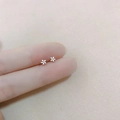 Detailed close-up showing miniature silver floral stud earrings against fingertips for scale - Flower / Silver
