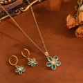 Parure florale avec collier doré et boucles d'oreilles en cristal bleu sur fond rétro - Ensemble de Fleurs en Zircone Bleue Dorée