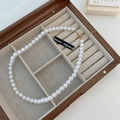 Detailed view of elegant white pearl necklace with golden lobster clasp in a wooden box - 8mm Pearl Style