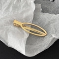Detail view of a polished golden oval alloy duckbill hair clip on a textured surface - Gold Oval Frame Style