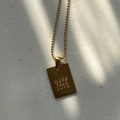 Detail of square gold pendant necklace with More Self Love engraving on a stone background - More Self Love / Gold