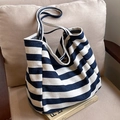 Blue and white striped canvas tote bag in a casual style placed on a sofa - Blue