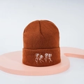 Détail du bonnet en tricot caramel montrant des broderies de squelettes dansant sur tissu côtelé - Couleur caramel