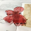 Pinza per capelli vintage rossa con motivo marmorizzato nero su sfondo di libro antico - Pizzo Rosso