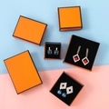 Flachbild von luxuriösen orangefarbenen Schmuckschatullen mit eleganten Ohrringen - Orange Schwarzer Rahmen / 5X5X3cm