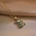 Detailed view of gold bear pendant with green and black zircons on brown satin background - Emerald Green Rhinestone Teddy Bear (23871)