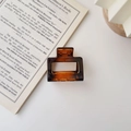 Amber square matte hair claw clip for women placed on a book against a white background - Glossy Amber