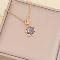 Close-up of gold sunflower necklace with a blue gemstone center in a beige gift box - Royal Blue