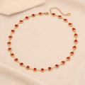 Close-up of heart-shaped gold necklace with red gemstones and lobster clasp detail - Red Marble