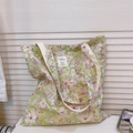 Detail of floral canvas tote bag featuring green flower patterns and white shoulder straps - Light Green with White Flowers