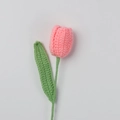 Detailed view of handmade pink crochet tulip flower with green knitted leaf on white background - Finished Closed Tulip (peach Pink)