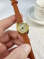 Detailed close-up of a women's quartz watch with a gold case and brown leather strap - Brown Strap Gold Dial