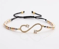 Detalle de pulsera tejida negra ajustable con símbolo infinito de circonita y cuentas de metal - Cuentas Tricolores (Oro/Plata/Oro Rosa) + Cuerda Negra