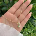 Close-up of 18K gold dragon pendant with sparkling green zircon crystals on a bead chain - Emerald Green