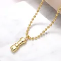 Collier avec pendentif poing plaqué or poli et chaîne à billes sur fond de marbre - Poing / Or