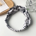 Detail of white paisley headband featuring twisted knot design and elastic back strap - White