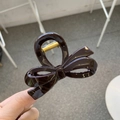 Detail view of a dark coffee bow-shaped hair claw clip with a glossy resin finish - Approx. 8cm / Chocolate