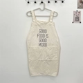 Detail of off-white canvas kitchen apron featuring large front pockets and letter print - GOOD FOOD IS White