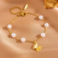 Elegant gold butterfly bracelet with white pearl accents on champagne satin background - Butterfly Bracelet