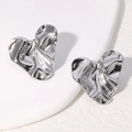 Minimalist silver heart stud earrings with wrinkled texture on white background - Steel