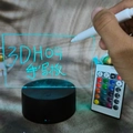 3D LED message board with black base and remote control showing cyan glowing letters - White Base Rechargeable 3-Color - Rectangle