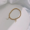 Detail shot of a gold pearl bracelet with a hollow star pendant on a white tray - Gold-Starlight