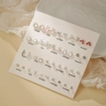 Lot de boucles d'oreilles variées avec cœurs nœuds et perles sur une carte blanche - E1952-1