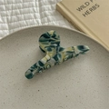 Detail van kleurverloop acetaat haarklem met marmertextuur op een decoratief bordje - Donkergroen