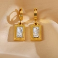 Close-up of gold geometric earrings with rectangle step-cut white zircon on beige silk - White