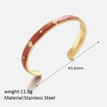 Detail view of gold stainless steel bangle with red enamel inlay and star accents - Red