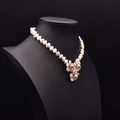 Collier de perles baroques vintage avec pendentif fleur blanc et rose sur un buste noir - Collier de Perles à Trois Fleurs