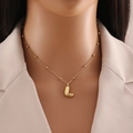 Golden bubble letter L pendant necklace with beaded chain on a model neck - Letter L