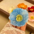Blue mesh fabric flower hair clip with yellow stamen shown in a variety of colors - Blue Poppy