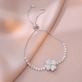 Detail of silver rotating clover bracelet with sparkling zircons on pink silk background - Silver Bracelet / Silver