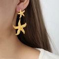 Starfish gold-plated drop earrings featuring a unique double starfish design on model - Gold