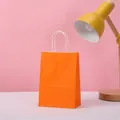 Eco-friendly orange kraft paper gift bag with white twisted handles in a minimalist setting - 15*11*6 / Orange