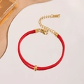 Minimalist red woven bracelet with gold beads and adjustable clasp on reflective surface - Red Cord Small Gold Bean Style (5344)