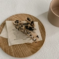 Detalle macro de la pinza de pelo de acetato con estampado de carey sobre lino y madera - Leopardo Claro