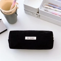 Close-up of black corduroy pencil case with woven label on a minimalist desk setup - Black