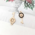 Close-up of two golden alloy key pendants with black enamel for DIY jewelry making - Key