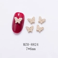 Detailed view of 7x6mm golden mini butterfly nail charms with pearls on red nails - Gold Butterfly With Pearl (8824)
